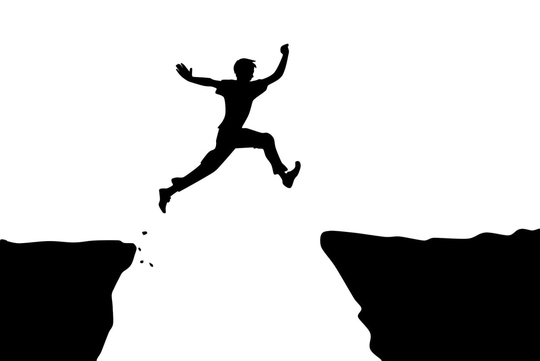 Man jumping over a crack in the land.  He jump to the other side.